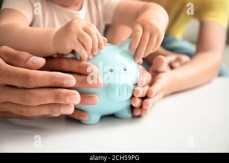 Familie mit Sparschwein am Tisch Stockfoto