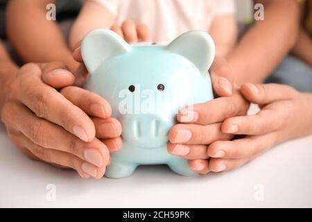 Familie mit Sparschwein am Tisch Stockfoto
