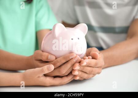 Familie mit Sparschwein am Tisch Stockfoto