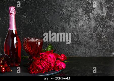 Flasche und Gläser Champagner mit Kirsche und Blumen auf Dunkler Hintergrund Stockfoto