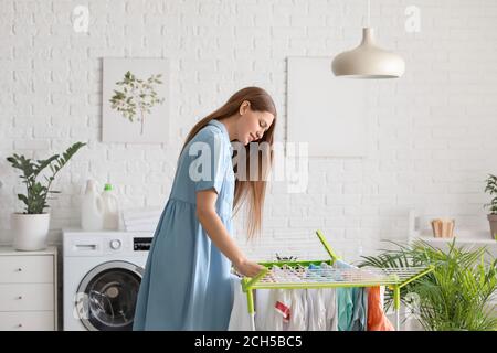 Frau hängend saubere Kleidung auf Trockner in der Waschküche Stockfoto