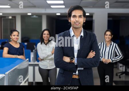 Selbstbewusster indischer Geschäftsmann, der vor seinen Bürokollegen steht, selektiver Fokus, Unternehmensumfeld, Teammitglieder, Geschäftsbüro. Stockfoto