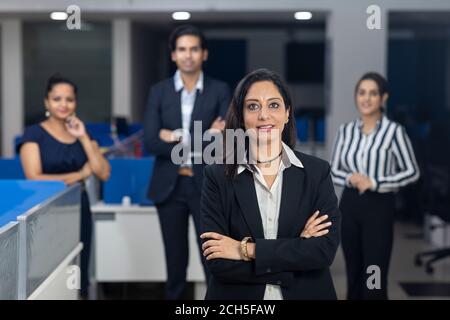 Selbstbewusste indische Geschäftsfrau, die vor ihren Bürokollegen steht, selektiver Fokus, Unternehmensumfeld, Teammitglieder, Geschäftsbüro. Stockfoto