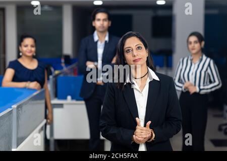 Selbstbewusste indische Geschäftsfrau, die vor ihren Bürokollegen steht, selektiver Fokus, Unternehmensumfeld, Teammitglieder, Geschäftsbüro. Stockfoto