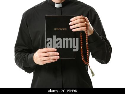 Hübscher Priester mit Bibel und Rosenkranz auf weißem Hintergrund Stockfoto