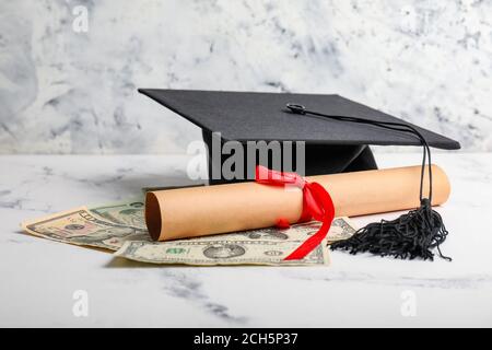 Geld, Diplom und Abschlusshut auf dem Tisch. Studiengebühren Konzept Stockfoto