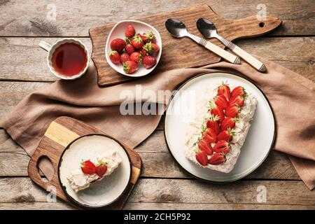 Köstliche Meringue Rolle mit Erdbeere und Tee auf dem Tisch Stockfoto