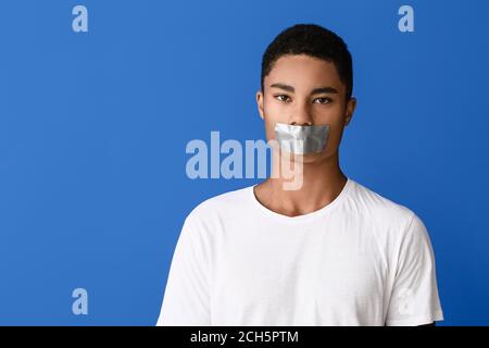 Traurige afroamerikanische Teenager mit aufgeklebtem Mund auf farbigem Hintergrund. Stoppen Sie Rassismus Stockfoto