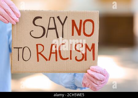 Frau hält Plakat mit Text SAGEN NEIN ZU RASSISMUS im Freien, Nahaufnahme Stockfoto