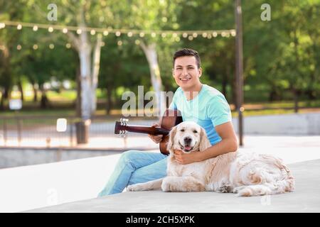 Junger Mann mit niedlichem Hund zu Fuß im Freien Stockfoto