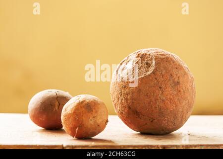 Nahaufnahme von uralten Schlammbällen auf Holztisch an cremefarbener Wand im Hintergrund sind uralte Schlammbälle in einem lokalen Museum von Sing Buri, Thailand ausgestellt. Stockfoto