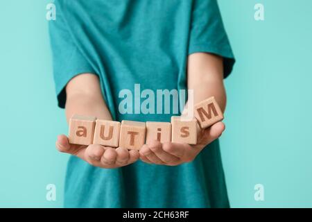 Kleiner Junge mit autistischen Störungen und Würfeln auf farbigem Hintergrund Stockfoto