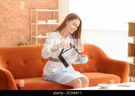 Frau gießt heißes gekochtes Wasser aus dem Wasserkocher in die Tasse Zu Hause Stockfoto