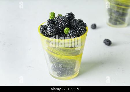 Tasse mit leckeren Brombeeren auf weißem Hintergrund Stockfoto