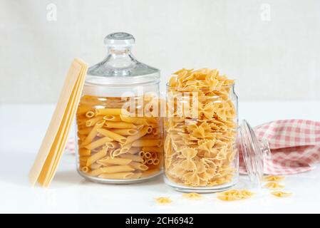 Italienische Nudelsammlung auf weißem Tisch. Rohpastakomposition. Italienische Küche. Penne, Fusilli und rohe Lasagne Stockfoto