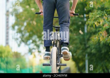 BMX in Moskau öffentlichen Park. Tapferer junger Biker, der Stunt macht. Er macht Trick auf dem Fahrrad im Sommer Tag. Extremsport ist bei Jugendlichen sehr beliebt. Rückseite/REA Stockfoto