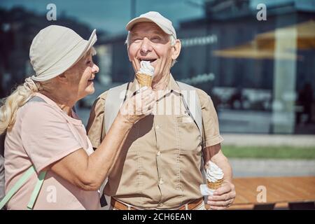 Zufriedener Mann, der Dessert aus der Hand seiner Frau isst Stockfoto