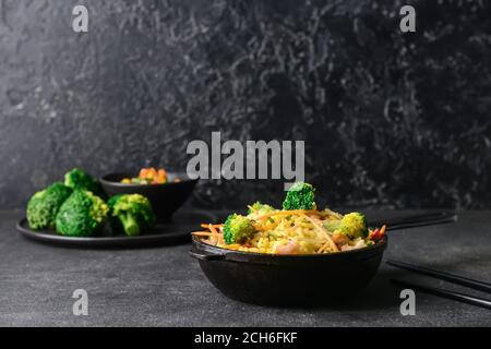 Bratpfanne mit leckerem Reis und Gemüse auf dunklem Hintergrund Stockfoto