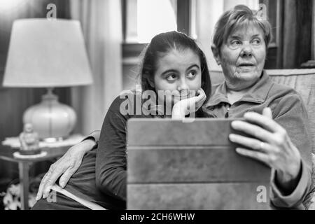 Junges Mädchen spielt mit Tablet mit ihrer Großmutter zu Hause. Stockfoto