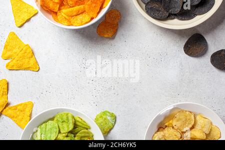 Verschiedene Arten von Kartoffelchips in weißen Schalen, grauer Hintergrund. Fast-Food-Konzept. Stockfoto