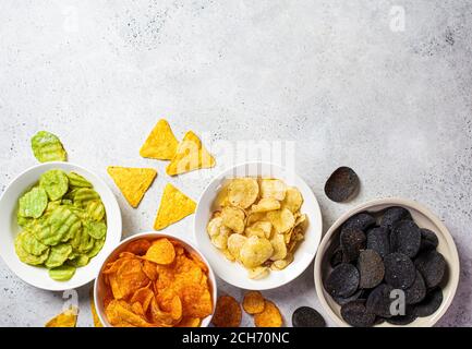 Verschiedene Arten von Kartoffelchips in weißen Schalen, grauer Hintergrund. Fast-Food-Konzept. Stockfoto