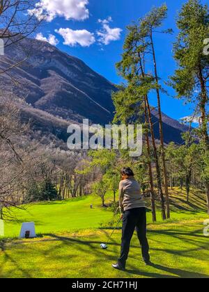 Golfer Abschlag mit Fahrer und mit Blick auf die Berge in Italien. Stockfoto