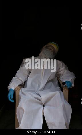 Erschöpfter Arzt in PSA Anzug Uniform in Stress auf schwarzem Hintergrund. Depression, müde Konzept. Stockfoto