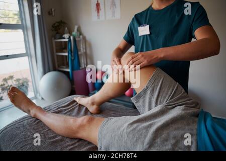 Nahaufnahme der jungen weiblichen Physiotherapeutin Hände geben Beinübungen zu Patient in der Klinik Stockfoto