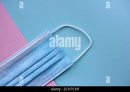 Medizinische Einweg-Gesichtsmaske auf blauem und rosa Hintergrund mit Kopierraum. Pandemie-Schutzhülle. Stockfoto