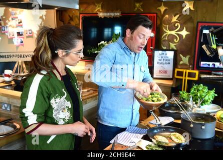 Jamie Oliver (rechts) kommt zu Cheryl an seiner Cookery School im Westfield Shopping Centre in London, als sie eine Facebook-Live-Veranstaltung starten, bei der Köche aus zehn Ländern die Zuschauer ermutigen werden, gesunde Gerichte von Grund auf zu kochen. Am Tag der Lebensmittelrevolution, der Teil der Kampagne zur Lebensmittelrevolution ist, die darauf abzielt, die Probleme der Unterernährung von Kindern und Adipositas anzugehen. Stockfoto