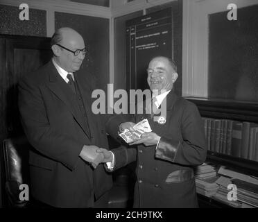 Lächelnder Busfahrer mit zehn £1-Noten ist Albert Edward Gunter, der 'die Lücke sprang', als Londons Tower Bridge öffnete, während sein Bus sie überquerte. Die Belohnung, die John B. Burnell, Operating Manager der Central Road Services von London Transport, in der Londoner Verkehrszentrale in Westminster überreichte, war ein Geschenk des Verwaltungsrats, um seinen Heldentum zu würdigen. Stockfoto