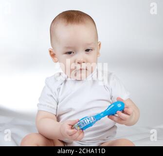 Foto eines zehn Monate alten Jungen mit blauer Rassel Stockfoto