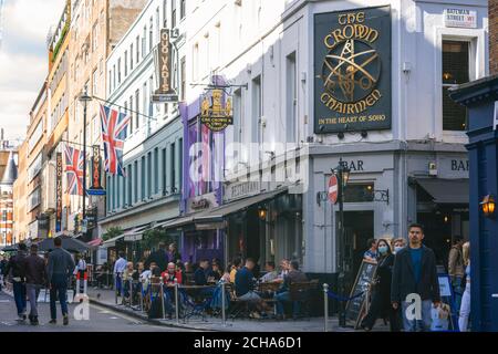 Kunden, die vor dem Crown and Two Chairmen Pub in der Dean Street in Soho, London, England, UK sitzen, während die COVID 19-Beschränkungen in sozialer Distanz gelten Stockfoto