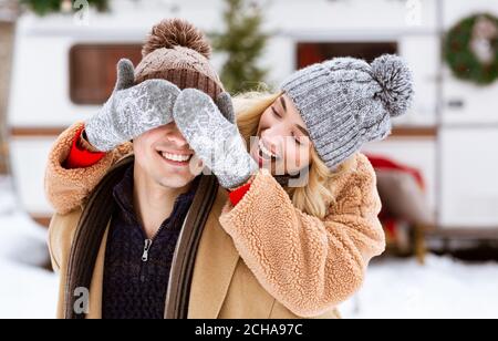 Outdoor Winter Portrait der fröhlichen jungen Frau, die die Augen des Freundes bedeckt Mit Händen Stockfoto