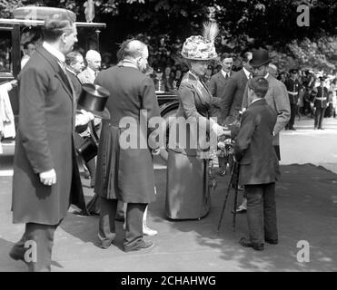 König George V. und Königin Mary bei ihrem Besuch in Rotherham. Ein Junge mit einer körperlichen Behinderung überreicht Queen Mary einen Blumenstrauß. Stockfoto