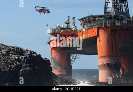 Ein Küstenhubschrauber winket einen Bergungsexperten an Bord des 17000-Tonnen-Bohrgeräts Transocean Winners, nachdem es am Strand von Dalmore im Carloway-Gebiet der Isle of Lewis auf Grund gelaufen ist. Stockfoto