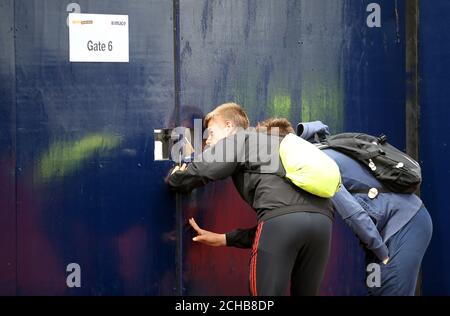 Ventilatoren schauen durch ein verschlossenes Tor auf die Bauarbeiten an White Hart Lane Stockfoto