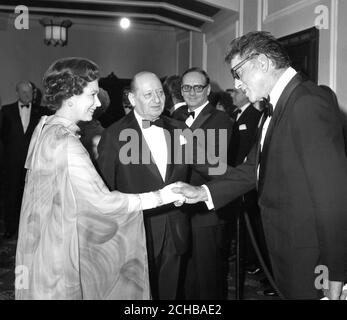 Queen Elizabeth II schüttelt die Hände mit Hollywoods Burt Lancaster im Dominion Cinema in London bei einer Royal Premiere seines neuen Films Moses. Looking On ist Sir Lew Grade, der den Film präsentiert, der in Großbritannien von Scotia-Barber Distributors veröffentlicht wird. Die Premiere unterstützt den British Olympics Appeal Fund. Stockfoto