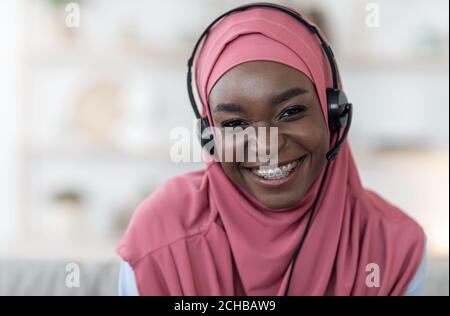 Porträt der afrikanischen muslimischen Frau in Hijab und Headset an Zu Hause Stockfoto