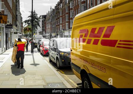 London - September 2020: DHL-Lieferperson und ein DHL-Lieferwagen auf der Londoner Straße Stockfoto