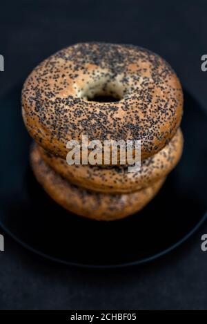 Schwarzer Teller voller Bagels auf schwarzem Hintergrund Stockfoto