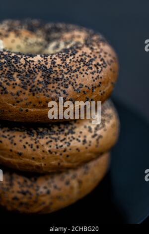 Schwarzer Teller voller Bagels auf schwarzem Hintergrund Stockfoto
