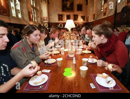 183 Universitätsstudenten, Mitarbeiter und Anwohner der Exeter College Dining Hall in Oxford brechen den Rekord für „die meisten Menschen, die Eiersoldaten gleichzeitig eintauchen“, der zuvor auf 178 eingestellt war. Stockfoto