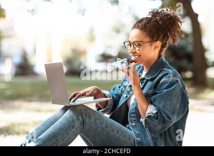 Mädchen Sprechen Auf Handy Mit Lautsprecher Arbeiten Auf Laptop Im Freien Stockfoto