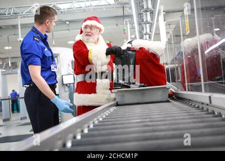 REDAKTIONELLE VERWENDUNG NUR EIN Mann, der als Weihnachtsmann am Flughafen Gatwick durch die Sicherheitskontrolle geht, während easyJet von Dezember 19 bis Heiligabend auf über 100 europäischen Flügen Fluggrotten einführt. DRÜCKEN SIE ZUORDNUNG. Foto. Ausgabedatum: Dienstag, 19. Dezember 2017. Sicherheitskräfte inspizierten den Geschenken des Weihnachtsmanns, als er sich vorbereitete, an Bord eines easyJet Airbus A320 zu gehen, um Passagiere zu überraschen. 20,000 Passagiere erleben die neuen festlichen Grotten an Bord und treffen den Weihnachtsmann auf Strecken von Großbritannien nach Frankreich, Deutschland, Italien, Portugal, Spanien und den Niederlanden. Bildnachweis sollte lauten: Matt Alexander/P Stockfoto