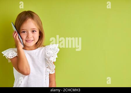 Schöne hübsche Mädchen sprechen am Telefon mit jemandem, kaukasischen Mädchen teilen Nachrichten, erzählen Geschichten an Freunde auf dem Smartphone, isoliert im Studio mit grünem Hintergrund Stockfoto