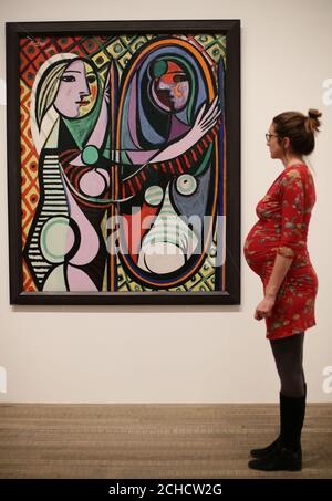 A Woman looking at Pablo Picassos Girl before a Mirror, 1932, während einer Vorschau auf die Ausstellung Picasso 1932 - Love, Fame, Tragedy in der Tate Modern in London. Stockfoto