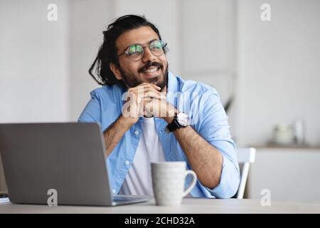 Nachdenkliche Freiberufler denken über etwas während der Arbeit an Laptop an Heimbüro Stockfoto