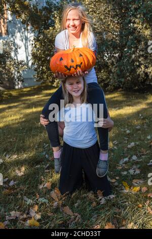 Wo Mädchen, blonde Haare, Freundinnen, neben einem großen Kürbis für Halloween. Hochwertige Fotos Stockfoto