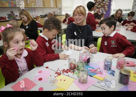 NUR REDAKTIONELLE VERWENDUNG (von links nach rechts) Poppy, Jayden und Kobi mit Janet Ellis, die den Schülern der 2. Klasse der Alderton Infant School kostenlose Knöpfe geliefert hat. Die Knöpfe wurden von Hobbycraft gespendet, um ihre neue Great British Button Challenge zu starten, die alle Kinder zum Nähen bringen soll und lernen soll, einen Knopf zu nähen, Loughton, Essex. Stockfoto